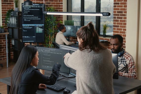 personne aidant une autre personne devant du code informatique