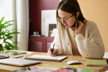 Jeune femme a son bureau en train de prendre des notes. 