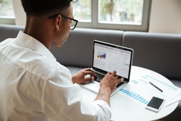 jeune homme avec lunette concentré sur son ordinateur tableau de donnée data visualisation