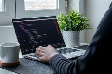 Bureau avec un ordinateur ouvert et montrant des lignes de code. 