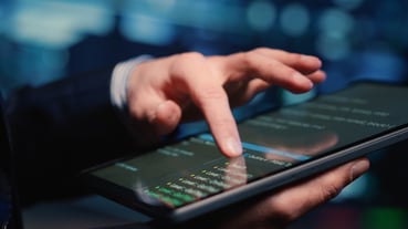 Un administrateur système inspectant des données massives sur une tablette dans un centre de données moderne.