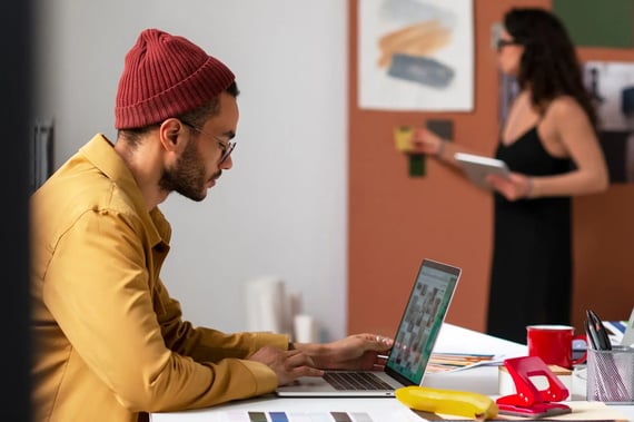Un jeune webdesigner travaille sur son ordinateur portable, concentré sur son écran.