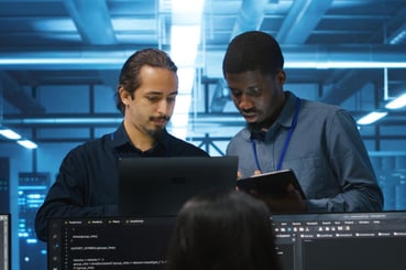 Deux administrateurs DevOps échangent sur un sujet tech en regardant tous les deux un ordinateur.
