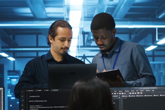 Deux administrateurs DevOps échangent sur un sujet tech en regardant tous les deux un ordinateur.