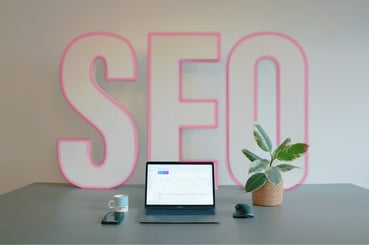 Ordinateur posé sur une table avec le mot SEO en fond.
