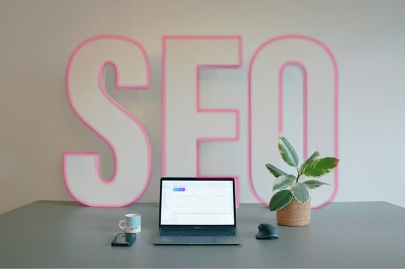 Ordinateur posé sur une table avec le mot SEO en fond.